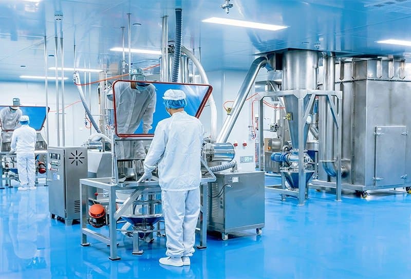 Operators in cleanroom suits at powder-processing equipment
